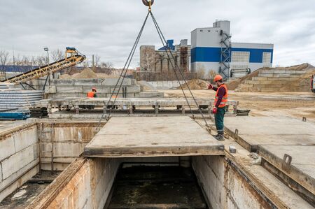 Lifting a concrete slab using a crane. Worker controls the lifting process.のeditorial素材