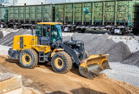 A wheel loader picks up gravel into a bucket. Transportation of inert materials for concrete...