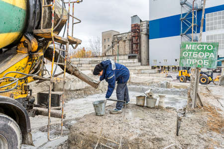 The laboratory assistant is preparing to take a concrete sample from the concrete mixer machine.のeditorial素材