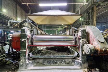Factory for the production of conveyor belts. Rubber rolling machine, close-up, large steel rollers.