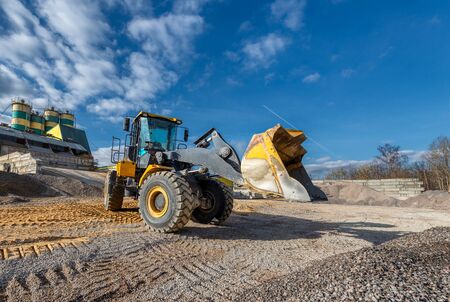 Wheel loader works in a warehouse of sand and gravel. Flyover for unloading railway freight cars.
