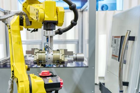 The hand of an industrial robot moves a detail of a connecting rod of an automobile engine.