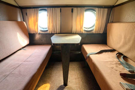 Interior of an old passenger plane. Luxurious vintage interior with wide and soft passenger seats.