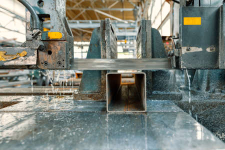 Band saw machine saws a steel square beam.の写真素材