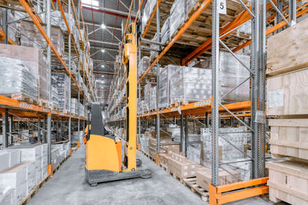 Large warehouse. Tall and long metal racks filled with various boxes, containers and drawers