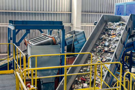 Waste sorting and recycling plant. Wide inclined conveyors filled with various types of waste