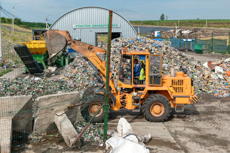 A bucket loader pours broken glass bottles. Disposal of household glass waste.のeditorial素材