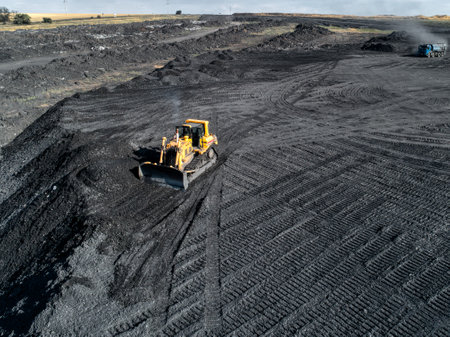 Bulldozer is pushing hard coal. Large coal heap.