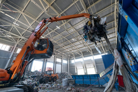 Waste sorting and recycling plant. Loader and grab crane are handling waste