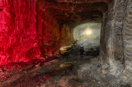 A miner examines a mine, illuminating the walls with his flashlightの写真素材