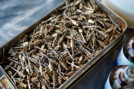 Thick steel needles for vaccinating large animals. Vials of vaccine stand nearby