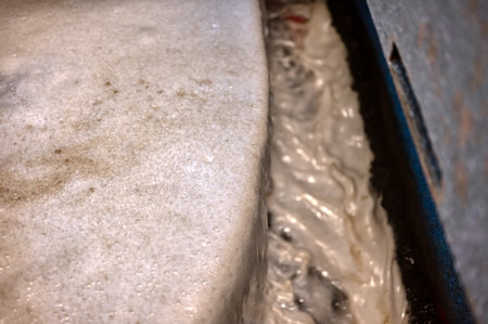 Flotation machine. A stream of gray, dirty foam flows from the separating edge of the bath into the...