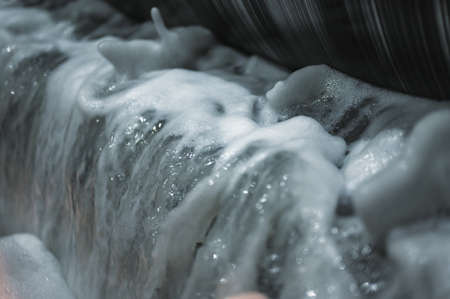 Metal drum of magnetic separator, bubbling and foaming water.