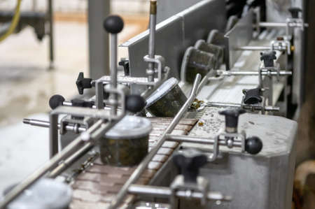 Seaweed salad in plastic jars on a conveyor belt. Automatic line for packing seafood
