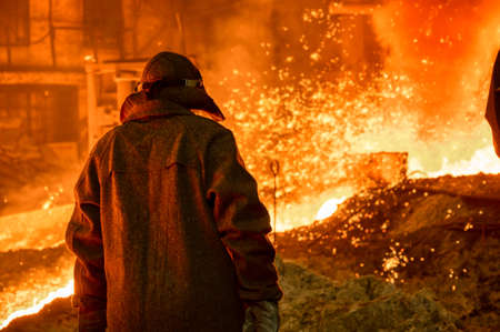 The process of releasing pig iron from a blast furnace. A man works with molten metal