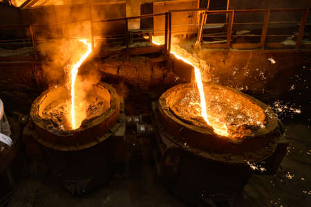An incandescent stream of metal pours into the ladles