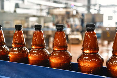 Plastic bottles with light filtered beer on the conveyor. Industrial production of beer.