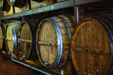 Line of wooden barrels of expensive alcohol drinks at plant