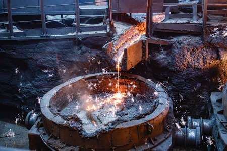 Molten iron flow. Liquid metal is poured into the ladle in a thin stream