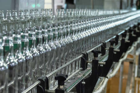 Conveyor with line of bottles for alcohol drinks in shop