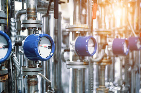 Flowmeters with arrows in blue cases on pipes in workshop