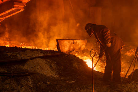 The process of releasing pig iron from a blast furnace. A man works with molten metal