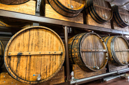 Racks with wooden casks of upscale alcohol drinks in cellarの写真素材