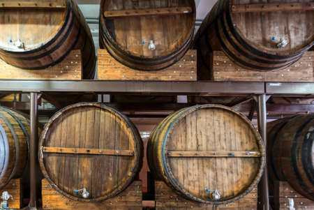 Line of wooden barrels of expensive alcohol drinks at plant