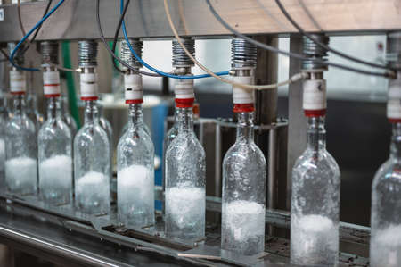 Filling glass bottles with vodka drink on production line