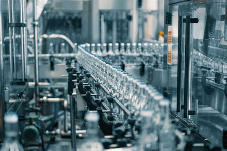 Closed glass bottles of upscale vodka transported by lineの写真素材