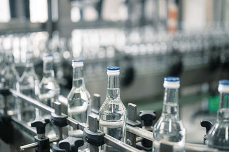 Closed glass bottles of upscale vodka transported by line