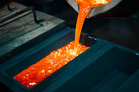 Pouring red molten silver metal into graphite casting formの写真素材