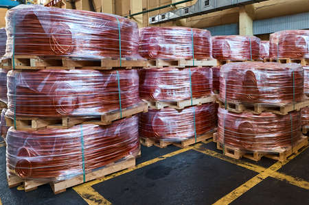 Coils of copper wire on wooden pallets in plant warehouse