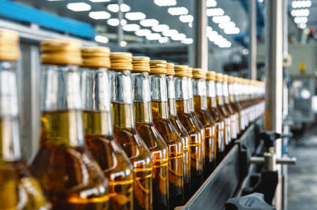 Alcohol liquor closed bottles with caps at production lineの写真素材