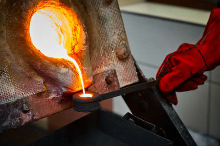 Worker takes sample of liquid gold from furnace for testsの写真素材