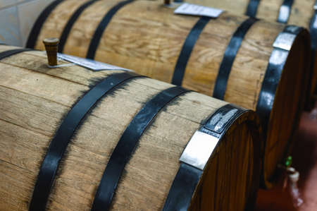 Huge wooden barrels of alcohol drinks on racks in cellarの写真素材