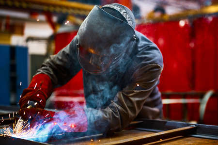 Laborer in protective mask welds manually metal frameの写真素材