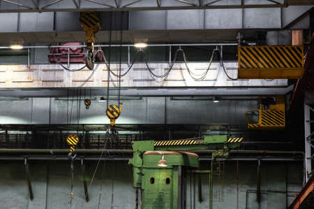 Overhead cranes with strong hooks under the ceiling of the industrial hall