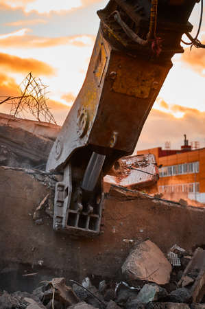 Modern crusher on excavator rigging dismantles concrete beamの写真素材