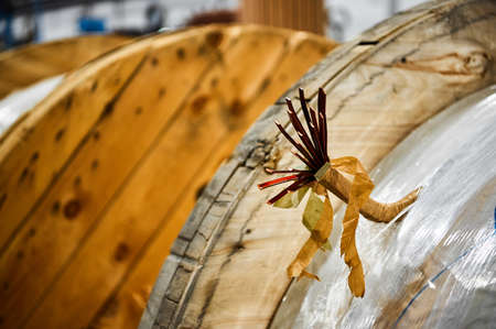 Wooden coil with thick copper wire. Part of the wire sticks out in a bundle.