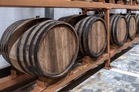 Huge wooden barrels of alcohol drinks on racks in cellar