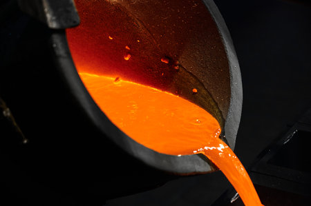 Pouring red liquid silver from bucket in induction oven