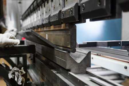 Bending machine operates with heavy metal plate in shopの写真素材