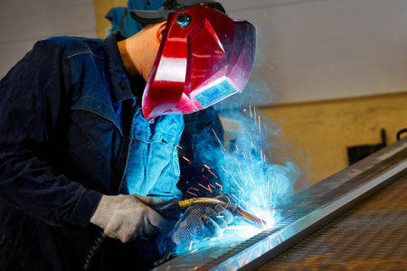 Employee with mask cuts beam with hot gas cutter at plant