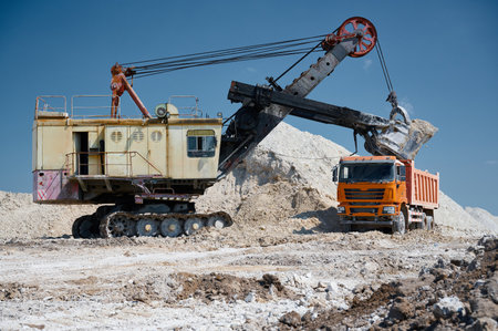 Shovel excavator loads chalk into tip truck at open quarry