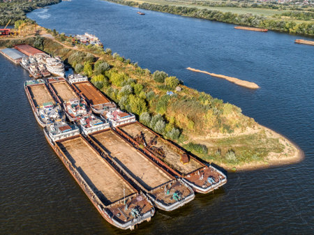 Dry cargo barges stand empty moored to green river islandの写真素材