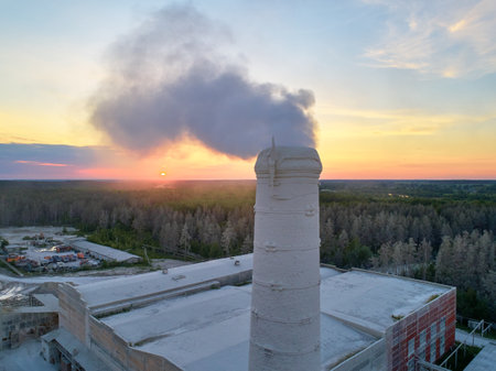 Steam rises up from brick chimney on production plant roofの写真素材