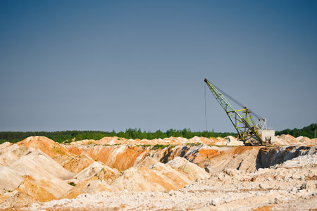 Walking excavator operates in chalk quarry with piles lineの写真素材