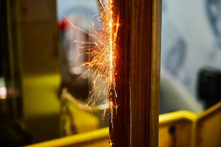 Electric erosion machining of metal beam with bright sparks