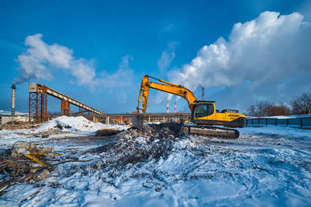 Bucket on excavator digs pit removing debris on winter dayの写真素材